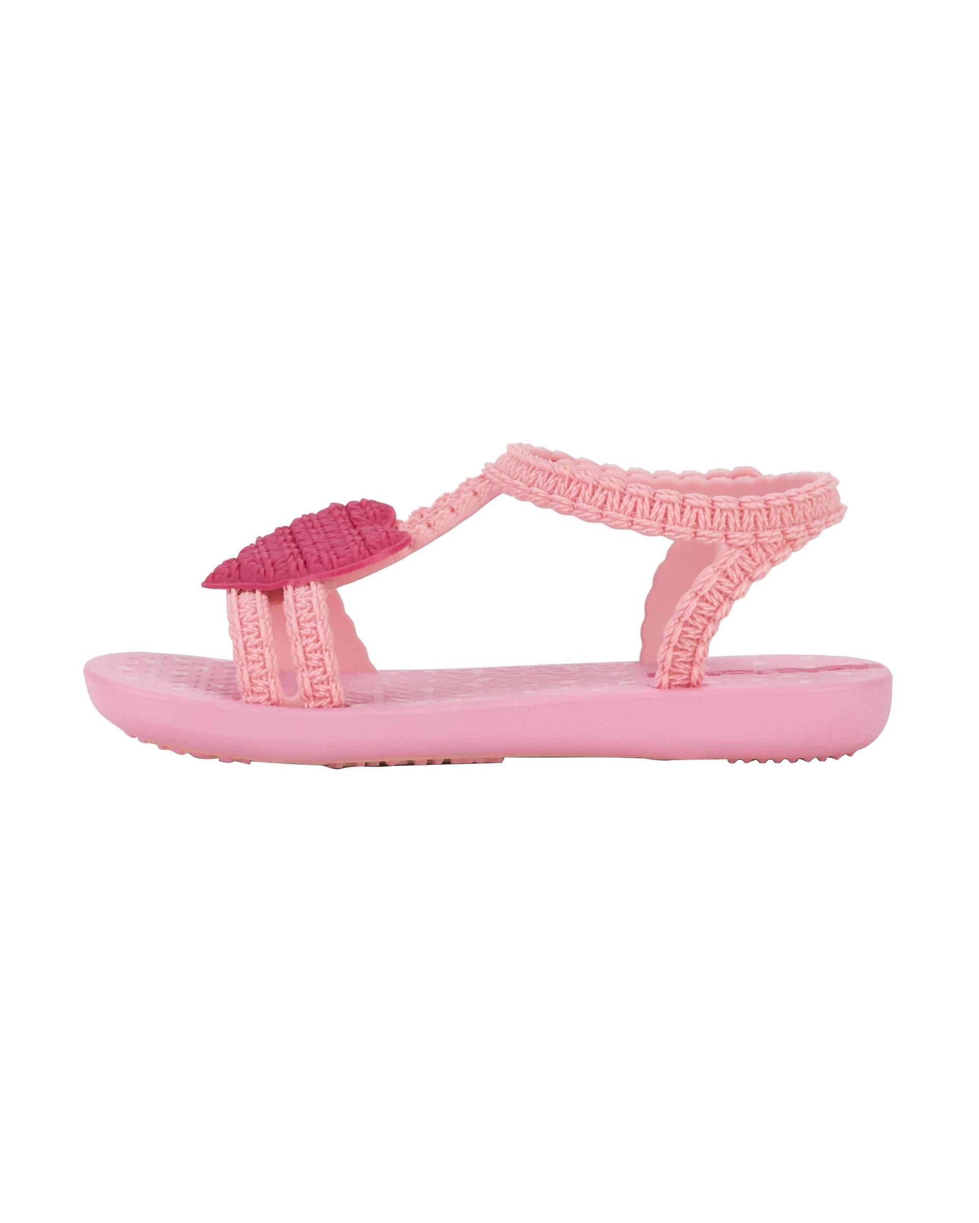 Inner side view of a pink Ipanema My First Ipanema baby sandal with pink heart on top and crochet texture .