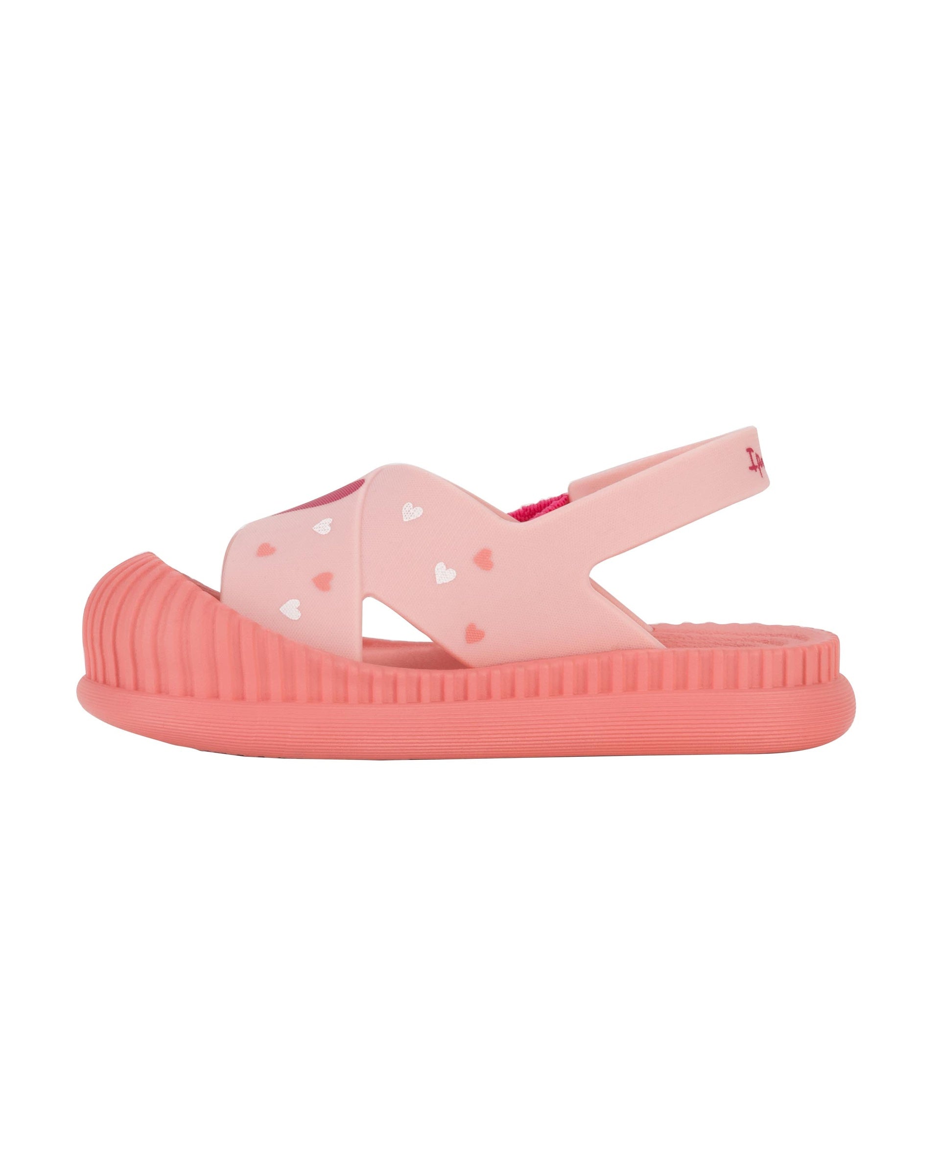 Inner side view of a pink Ipanema Cute baby sandal with hearts on the strap.
